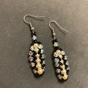 Svart och vita örhängen - Dessa har jag gjort själv.   De är gjorda av små svarta glaspärlor, genomskinliga glaskristaller på kangen och vaniljfärgade runda plast pärlor i mitten.   Örhänget är av metal.  Själva hänget är ca 4 cm lång.  Har aldrig använt