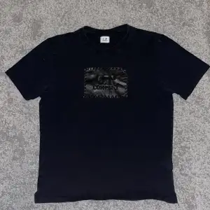 C.P. Company t-shirt med tryck på. Tröjan är i bra skick och har inga tecken på varken hål eller slitage! Nypris är runt 1 500 kr.