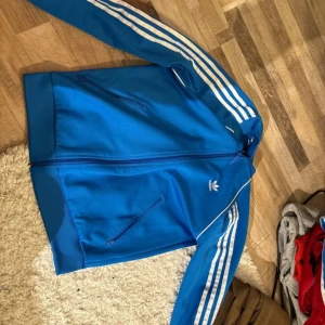 En blå adidas kofta  - Koftan är i väldigt bra skick då ja inte använt den så många gånger ja skulle säga att den är lite stor i storleken. Men säljer den då detta inte är min stil längre 