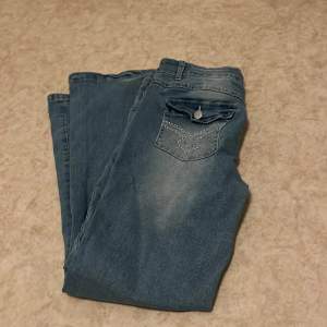 Helt oanvända blåa jeans med mönster på backfickorna. Storlek 38/M. 
