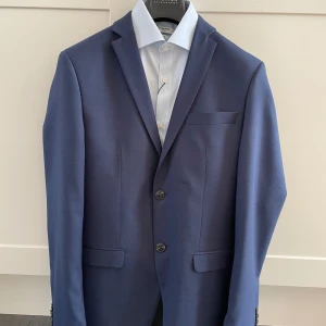 Jack and Jones kostym - Kavajen och byxor använda fåtal gånger. Skjortan aldrig använd, lapp sitter kvar. Premium Solaris super slim mörkblå storlek 44 Nypris 2200 för kostymen och 400 för skjortan 
