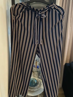 Byxor - Randiga marinblå byxor med inslag av gult och vitt, strl M Raka/vida med knyt i midjan 