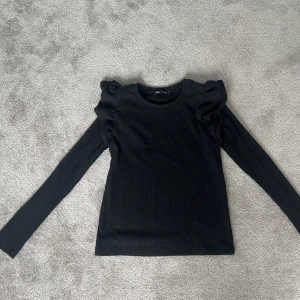 Topp från zara - Fin topp från zara med volanger på axlarna.