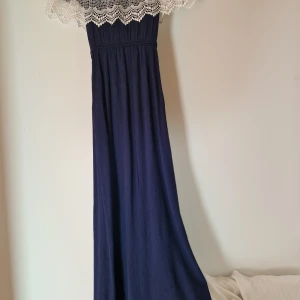 Elegant marinblå klänning  - Elegant klänning, mycket gott skick, "off the shoulder", "elastisk/strechy" tyg, marinblå med vit spets, väldigt somrig och passar både till formella och informella tillfällen. 