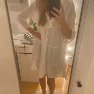 Kortärmad klänning - Vit kortärmad klänning i linne! Volanger och v- ringad krage