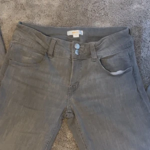 Gråa lågmidjade bootcut jeans🩶 - Gråa låg missade jeans från Gina tricot. Knappt använd. Nypris: 350kr. Innerbenet: 80cm midjan: 33cm. 🩶Jätte fina och är bootcut. Passar till allt och justerbar. Kontakta om intresserade eller om ni vill ha fler bilder.🩶