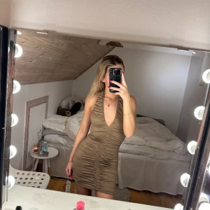 Klänning med detaljer  - Beige klänning med rynkade dejtajer både fram och bak. 