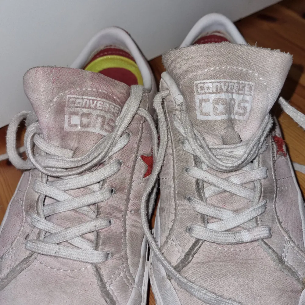 Låga sneakers i läder  med lite oklar färg, typ nött rosa och röda mockadetaljer. Superskön sula! Inte platta som andra Converse-modeller. Storlek 38. Är lite smutsiga men inte särskilt nötta. Säljer för att jag inte använder dem längre.. Skor.