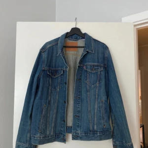 Levi’s denimjacka  - En klassisk denimjacka med knappar och fickor. Jackan har en normal passform och är perfekt för både vardag och fest.