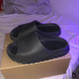 YEEZY SLIDES  - Säljer mina asfeta svarta yeezy slides, köpt från Jd sports drop för något år eller två. Har bytt email så kan tyvärr inte komm åt kvittot😅 Storlek 43 passar till mer eller mindre storlekar då det är yeezy🤙