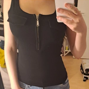 Svart tubtopp med dragkedja  - Svart tubtopp med dragkedja frpn Gina. Används några få gånger och är därför i nyskick.  Orginalpris:- 130kr 