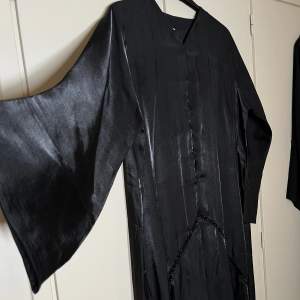 Oanvänd avart silkes abaya med pärlor. Strl 58. Passar någon bäst som är 168-175cm lång. Med knappar