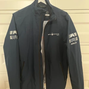 Vindjacka Sail Racing - Hej, detta är en vindjacka från sail racing med Gore-tex, alltså skyddar den mot vatten. Jackan är perfekt till vår och sommar på land och till havs! Storlek M