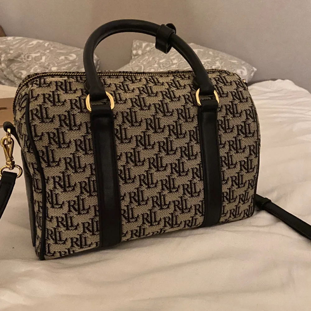 En svart Ralph Lauren handväska med monogram tryck, knappast användt och är i gott skick. Riktigt classy. Nytt pris 3,2k, säljer den 900kr +frakt💋. Väskor.