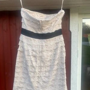 Kort finklänning utan axelband  - Kort klänning utan axelband. Spetstyg över. 