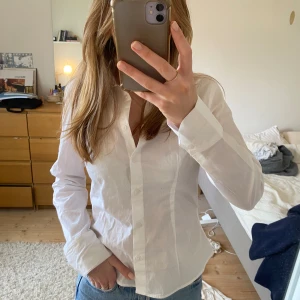 Skjorta - Vit lite figursydd skjorta från H&M i storlek S. Den är i mycket bra skick och säljer då den inte kommit till användning.