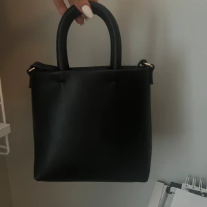 Svart liten väska  - Den e från hm från förra året, har ett långt band också till❤️är i bra skick!