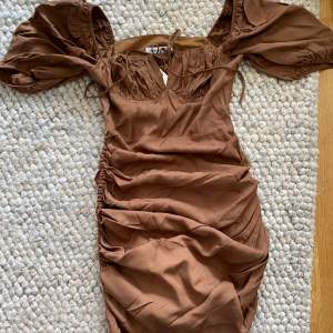 Säljer denna helt nya otroliga bruna klänningen då jag inte fått användning för den. Aldrig använd och alla lappar kvar. Sista bilden visar exakt samma klänning på fast svart☺️