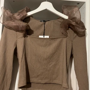 Topp  - Magtröja med axeldetaljer. Prislapp fortfarande på, nypris 259kr. Storlek M men passar även S. 