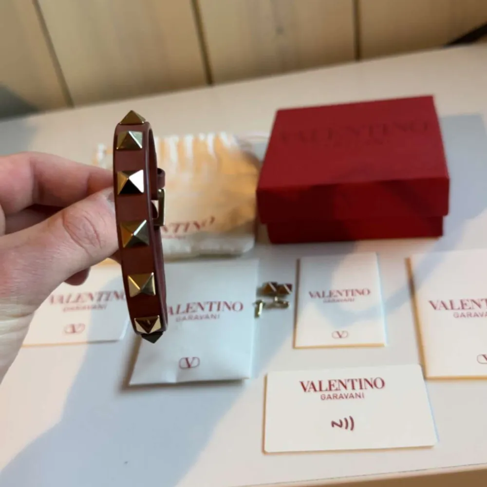 Ett riktigt snyggt Valentino armband i vinröd/brun. Armbandet är i riktigt bra skick, allt og tillkommer inklusive extra nitar. Inköpt på NK, bevis finns, hör av er vid minsta fundering!. Accessoarer.