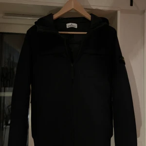 Stone island jacka - Stone island junior jacka marinblå. Strl 170/14 år. Använd fåtal gånger. Köpt på nk Nypris 4600kr Qr kod finns inuti jackan. Priset diskuterbart vid snabb affär.  Obs, ser mörkare ut på bilden än vad den är, den är marinblå  