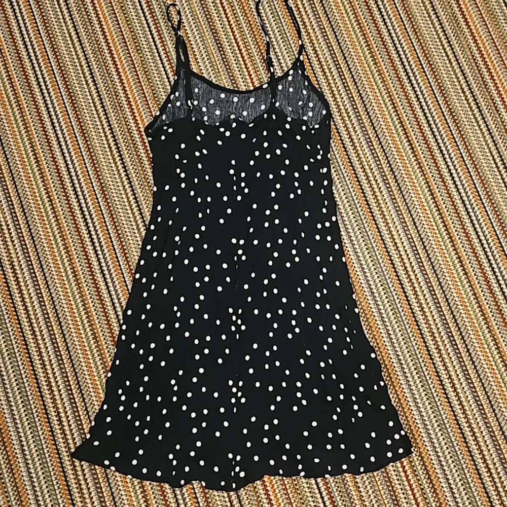 En mörkblå kläning som nästan ser svart ut och som har vita prickar på sig. Den har lite stretch i sig och en dragkedja där bak.. Klänningar.