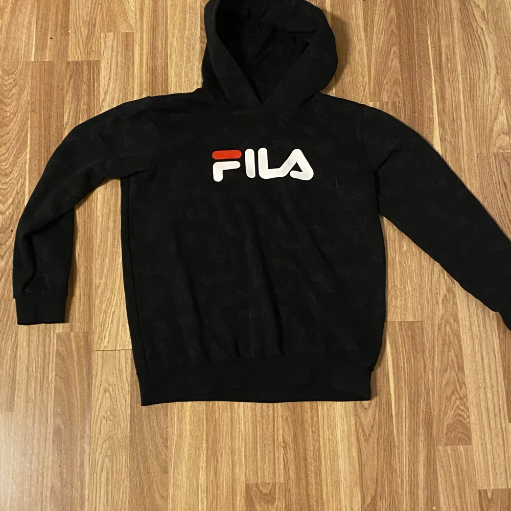 En svart FILA hoodie. Passar 13-15 åringar ( 13/14 är bäst rekommenderat). Hoodies.