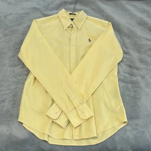 Ralph Lauren skjorta - Ljusgul Ralph Lauren skjorta i storlek 8 men passar snarare S och kanske M. Något blekare i färgen än den förra gula skjortan jag lade ut. Slim-fit modell och lite vintage vibe. Sparsamt använd och i gott skick