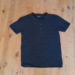 T-shirt med knappar - Använd men är i fint skick. Växde ur den, sitter riktig bra runt bröstkorgen.