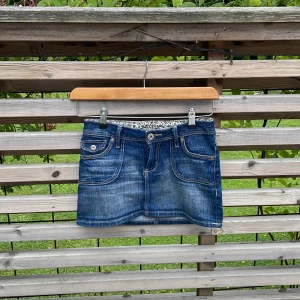 Jeanskjol - En jeanskjol från hm med utåtfickor på baksidan. Bra skick och säljer för att midjan har blivit för liten. Den har ett blomstermönster på översta innersidan. Storlek 140. Om den köps kommer den att strykas💕