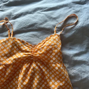 Klännikg - Orange klänning ifrån hm, perfekt till sommaren, vita blommor på, 