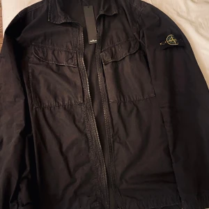 Stone island jacka  - STONE ISLAND flap-pocketlightweight jacket. storlek xl passar bra i storleken  Använd sparsamt och fåtal gånger och är i gott skick och inga tecken på skador. Väldigt praktiskt inköpt från farfetch och kvitto finns 