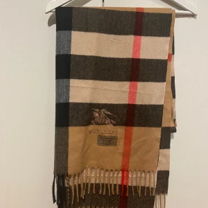 Burberry halsduk - En snygg och stilren Burberry halsduk, skick =  10/10🍾. Halsduken är gjord utav 100% kashmir. Hör av er med minsta fråga eller fundering!