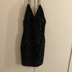 Glittrig festklänning - Fin glittrig klänning med smala axelband. Dragkedja i ryggen.  Helt ny, endast provad.