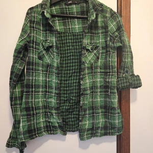Grönrutig skjorta - Grönrutig skjorta med fäste för att kunna ha ärmen upprullad (se vänster ärm). Använd men i mycket gott skick