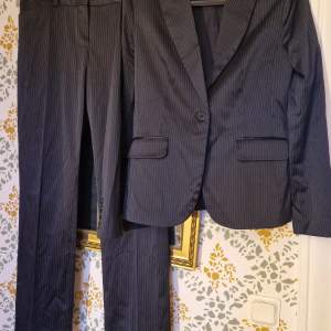 Snygg kostym! Perfekt till kontoret eller festen! MNG suit kavaj och byxor, båda i stl 42. Matchande svart set med diskreta ränder. Fint skick, använd enstaka gånger. Inga defekter.