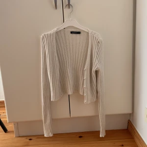 Kofta - Krämvit kort kofta med pärlknappar