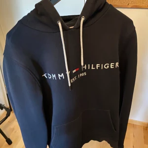 Tommy Hilfiger Hoodie (Svart) Stl: S - Säljer min Tommy Hilfiger hoodie då den blev för liten för mig. Köpte den i Mall of Scandinavia i Tommy Hilfigers butik för 1300kr.  Lite använd men har tagits hand om väldigt försöktigt och väl vid varje tillfälle.  Söker 780kr