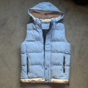 Baby blue väst med luva - 10/10 i skick, använd en gång men är för stor så har ingen användning för den.