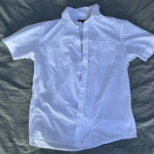 Kortärmad skjorta  - Köpt secondhand, har en liten märke på ryggen (se bild). 