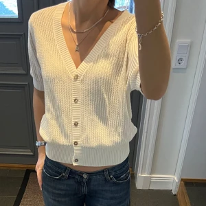 Vit trekvartsärmad kofta  - Stickad vit kofta från Lindex med knappar. Storlek M, passar även S. Fint skick. Använd gärna köp nu!