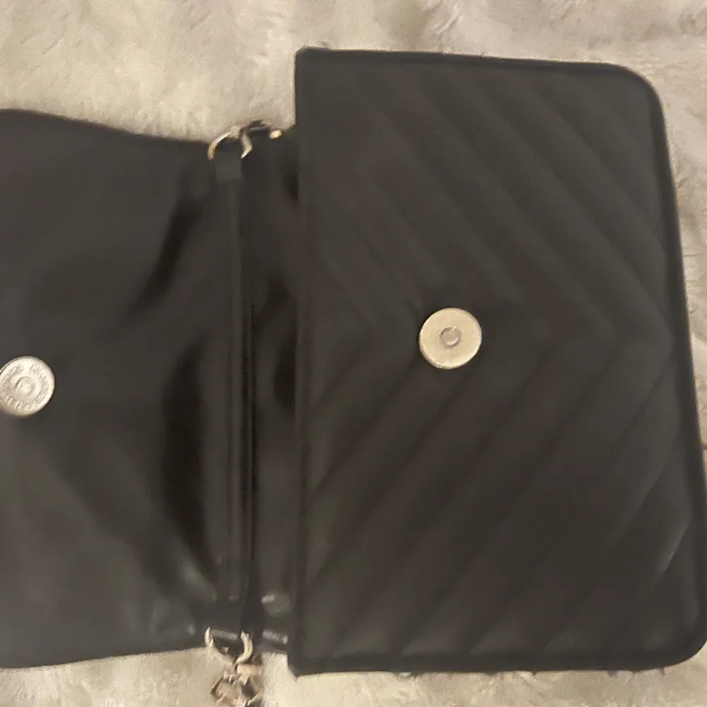 Jättefin svart crossbody bershka väska med silver kedja! Den är lite sliten på sidorna, annars  är den i fint skick💕 Orginaltrogen pris är från 200-300kr. Väskor.