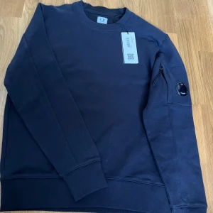 CP COMPANY HELT NY - Säljer denna Sprillans ny Cp company Sweatshirt som är köpt från thernlunds. Allt är kvar prislapp, ALDRIG använd och passar 162-175. Nypris 2299kr mitt pris 899💸 kan diskutera pris vid snabbaffär 💨 
