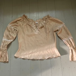 Beige Blus - Beige blus med spets. Storlek M men skulle säga att den passar M-L beroende på hur en vill att den ska sitta. Så fin och i bra skick men säljer för att den tyvärr inte kommer till användning. Hör av dig om du har några frågor! 