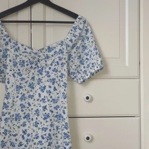 Klänning, blå vit mönstrad  - Klänning med blommigt mönster, köpt på vero moda. Den är i st M men skulle säga att den sitter som en S eller mindre M Den är i gott skick. Den går till knäna 