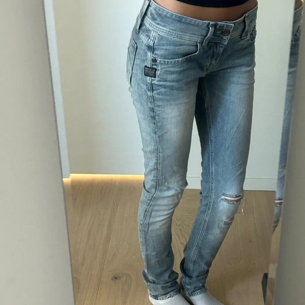 Grå/blå lågmidjade skinny jeans från G-star med slitningar på knäna (modell LYNN SKINNY WMN). Långa i benen (passar mig som är 176 cm) och i mycket fint skick. 🩶Nypris runt 1000kr.. Jeans & Byxor.