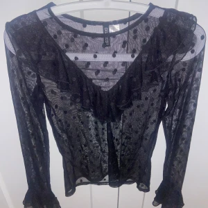 Svart transparent topp från Divided - svart transparent topp från Divided med prickigt mönster och volangdetaljer. Toppen har långa ärmar och en rund halsringning. Passar perfekt både till fest och till vardags, aldrig använt💕
