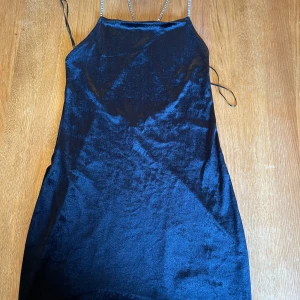 Svart mini klänning  - Kort svart bodycon klänning av sammetsliknande tyg. Öppen rygg med korsade axelband i strass. Fin men ganska kort. Förlåt för att sista bilden är av så dålig kvalitet men det är typ ända bilden jag har. Använd väldigt få gånger. Frakt ingår inte.