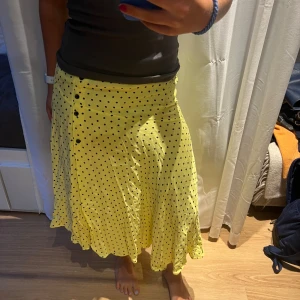 Lång kjol med slits - Lång kjol, gul med svarta prickar. Väldigt sommrig och fin. Hade själv på en skolavslutning men kommer ej till användning längre. Storlek XS men passar även S