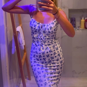 Långklänning  - Åtsittande vit långklänning med blåa blommor, använd fåtal gånger! 80kr stl xs